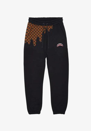 Pantaloni jogger neri con motivo a quadri arancioni e neri a goccia sulla parte superiore sinistra e una piccola grafica di bocca di squalo sulla coscia destra.