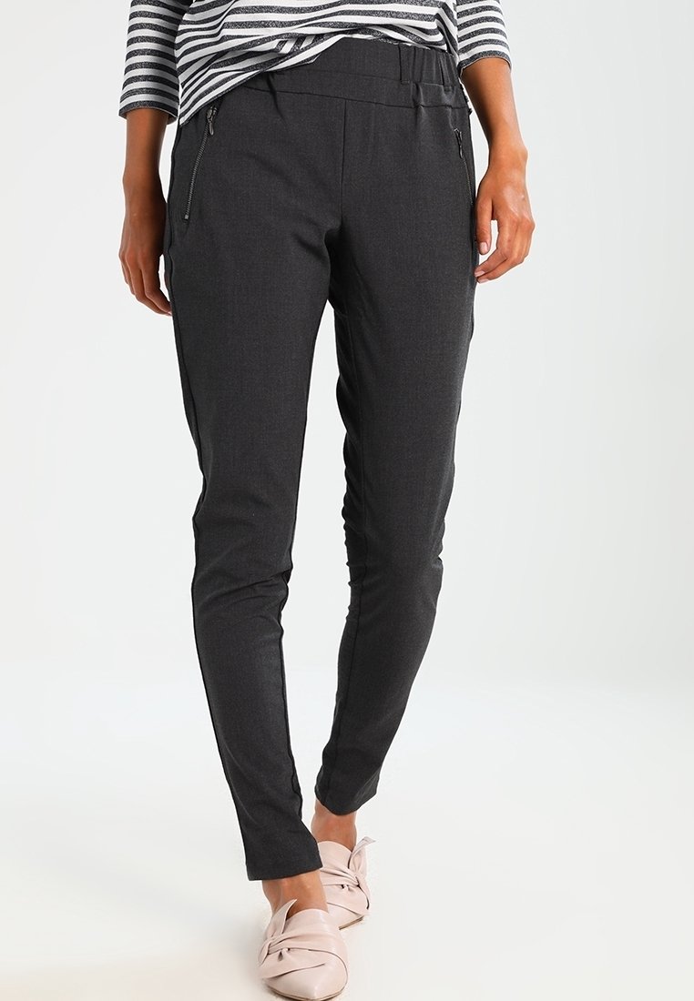 Pantalon gris foncé fuselé en tissu extensible avec zips latéraux, doté d'une taille plate et d'une coupe slim, associé à des chaussures rose pâle.