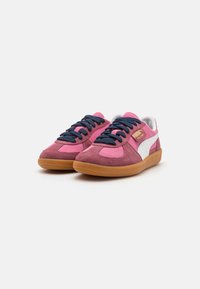 Růžové a fialové semišové tenisky s gumovou podrážkou, námořnickými tkaničkami a bílým bočním pruhem s logem značky.