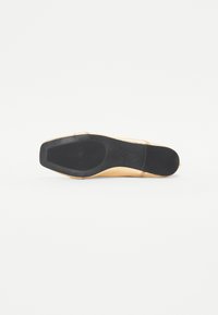 Suela de zapato de cuero marrón con base de goma negra, que presenta un patrón de agarre texturizado y una forma ligeramente curvada.