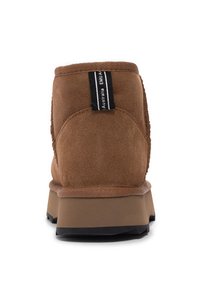 Stivale alla caviglia in suede marrone con colletto imbottito, dotato di un'etichetta in tessuto nera sul retro e una suola in gomma a contrasto.