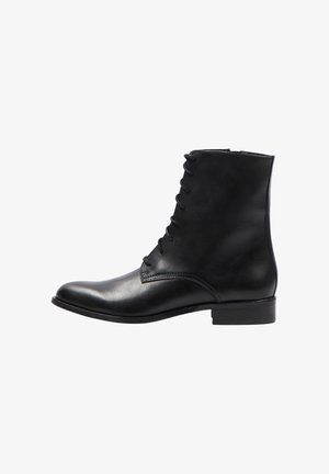 Musta nahkasaapas nilkkamittaisena, jossa on sileä pinta, pyöreä kärki ja nauhakiinnitys. Varustettu matalalla, lohkomuotoisella korolla ja vähäisellä tikkausdetaililla.