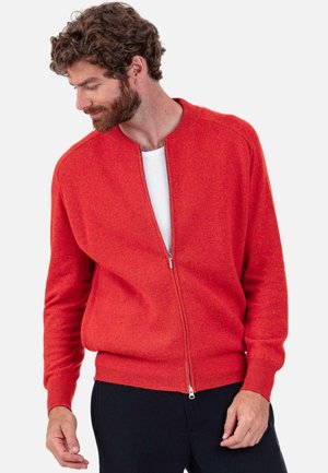 Red zip-up sweater with a round neckline, ribbed cuffs, and hem. Soft texture, fitted design, layered over a white shirt.