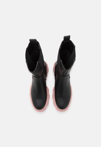 Botas de tobillo negras de cuero con un acabado suave, con suela de goma rosa y tiradores laterales para facilitar su uso.