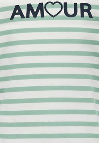 Top de tela ligera con rayas horizontales verdes y blancas. Presenta la palabra "AMOUR" en azul marino con una forma de corazón sobre la letra "O".