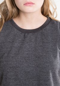 Sötét szürke pulóver kerek nyakkal, puha tapintással, enyhe redőkkel a nyaknál és bordázott mandzsettákkal. Egyszerű és laza dizájn.