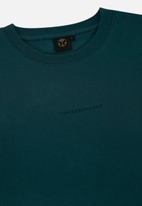 Tegengroen katoen t-shirt met een ronde hals. Voorzien van reliëftekst "TOMORROWLAND" aan de voorkant. Zachte textuur en een relaxte pasvorm.