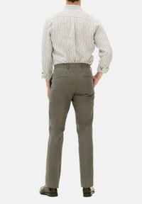 Graue, maßgeschneiderte Hose mit glatter Textur. Die Rückansicht zeigt dezente Steppnähte und eine schmale Passform. Kombiniert mit einem gestreiften Hemd.