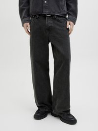 Jeans in denim nero con una vestibilità comoda, gambe dritte e una finitura leggermente zigrinata, indossati con scarpe chunky nere.