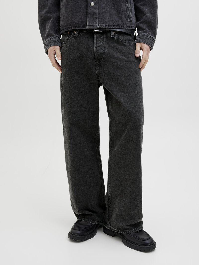 Jeans in denim nero con una vestibilità comoda, gambe dritte e una finitura leggermente zigrinata, indossati con scarpe chunky nere.