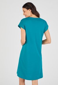 Vestito in cotone turchese con maniche corte, scollatura rotonda e una vestibilità comoda, caratterizzato da un orlo curvo e una trama liscia.