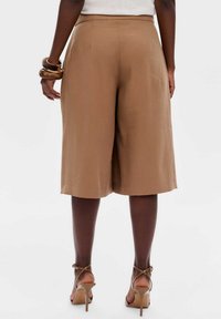 Bruine op maat gemaakte culottes met een gladde textuur, halflange snit en een lichte glans. Zichtbare achterzakken en een standaard tailleband.