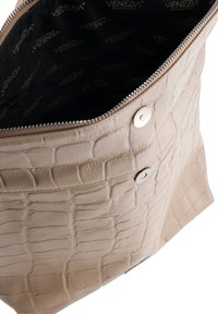 Beige krokodillepræget læder tote taske med sølvhardware. Lynlåslukning og mærkevare sort indvendig foring. Glat tekstur, rummeligt design.