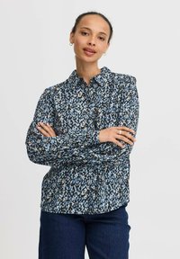 Camicia a maniche lunghe blu con motivo, dal taglio rilassato e colletto classico; presenta un tessuto testurizzato con forme astratte.