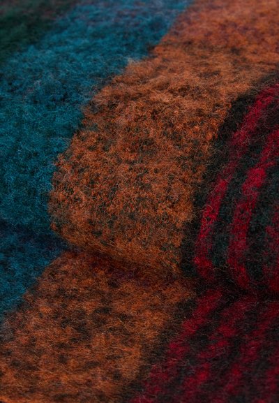 Textured wool fabric in blue, orange, and dark red hues, featuring a checkered pattern with a soft, fuzzy surface.