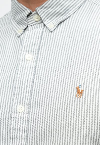 Proužkovaná košile na knoflíky v bílé a šedé barvě. Má špičatý límec a malý vyšívaný motiv koně. Měkká bavlněná látka.