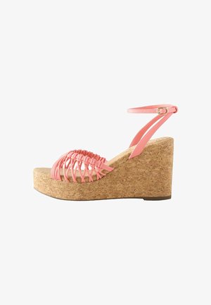 Wedge sandals with cork base, pink strappy elastic upper, and adjustable ankle strap. Features an open toe design and textured surface.