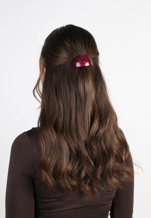 Lila Acryl-Haarklammer, die gewelltes braunes Haar hält, mit einer glatten, glänzenden Oberfläche und einem halbtransparenten Design.