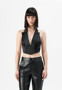 Top cropped de satin preto com decote em V profundo e gola estruturada, combinado com calças de couro preto de cintura alta com fecho de correr.