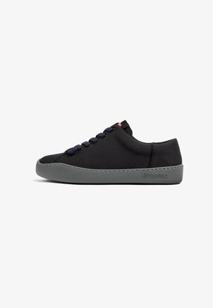 Black fabric sneaker with navy laces and gray rubber sole. Features a smooth upper and prominent stitching detail. Brand logo on the sole.