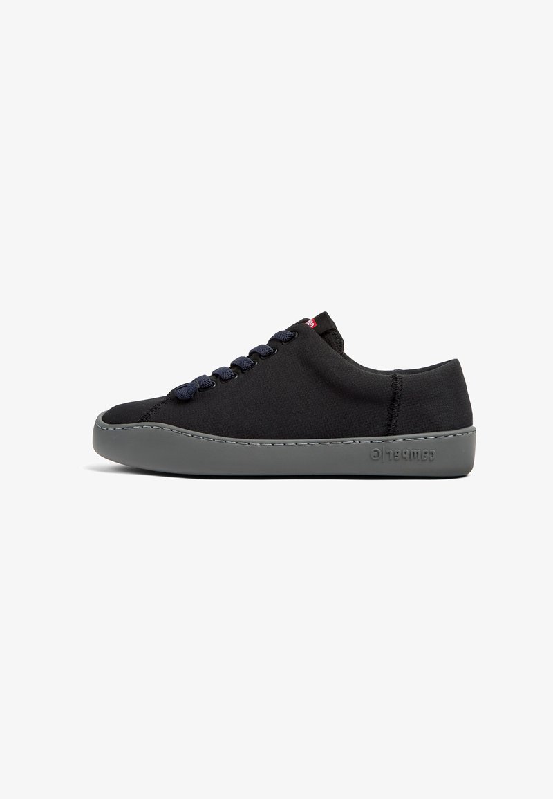 Svart tygsneaker med marinblå snören och grå gummisul. Har en slät ovandel och framträdande sömdetaljer. Logotypen finns på sulan.