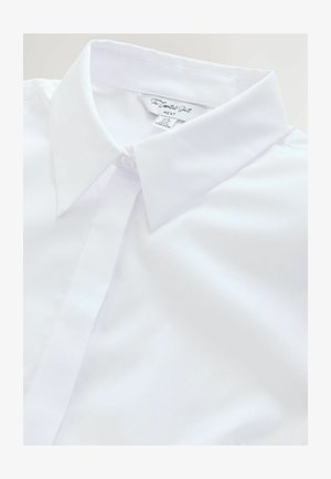 Valge nööpidega särk terava kraega, valmistatud siledast kangast. Omab eestpoolt nööpimist ja sildit lähedal krae. Ilma nähtavate mustriteta.