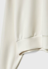 Crème-kleurige sweatshirt met een zachte, gladde textuur, ribbelmanchetten en een relaxte pasvorm. Geen zichtbare patronen of hardwaredetails.