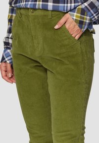 Groene corduroy broek met verticale ribbels, met zijzakken. De stof heeft een zachte textuur en een relaxte pasvorm.