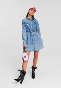 Jeans srajčna obleka z dolgimi rokavi, zategnjena v pasu z vrvico. V kompletu z črnimi patentnimi gležnjarji in majhno rožnato torbico.