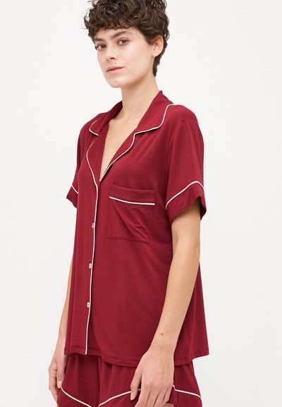 Βουργουνδής πιτζάμα με κοντό μανίκι, με λευκή ραφή, τσέπη και σχέδιο με κουμ�πιά μπροστά. Μαλακό ύφασμα με χαλαρή εφαρμογή.