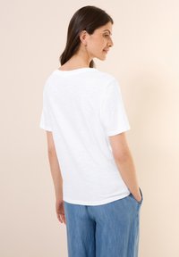 Hvid kortærmet t-shirt i let materiale, med en afslappet pasform og rund halsudskæring. Bagview med subtile tekstur detaljer.