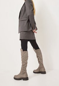 Szare botki sięgające za kolano, wykonane z miękkiego zamszu, z lekko opadającym krojem, gumową podeszwą oraz dyskretnym detalem suwaczka z boku.