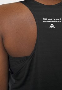 Zwart sportief tanktop met een gestructureerd ontwerp, een open rug en witte logotekst op de bovenrug, met een gestroomlijnde pasvorm.