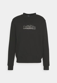 Felpa nera con collo rotondo, polsini e bordo a costine. La parte anteriore presenta "KARL LAGERFELD" in pietre brillanti, mettendo in risalto il marchio.