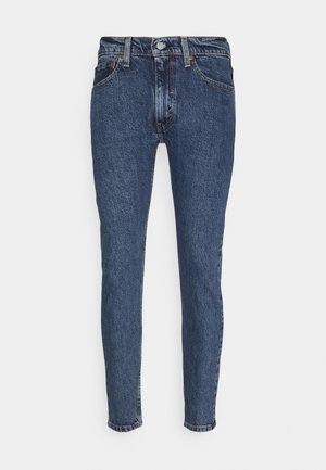 Niebieskie jeansy typu slim-fit z denimu, zapinane na guziki, z przednimi kieszeniami, szlufkami na pasek i delikatnym blaknięciem wokół szwów.