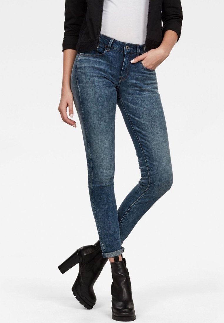 Slim jeans i mellanblå denim, med en lätt blekning, femfickorsdesign och hög midja, ihopparade med svarta ankelboots.