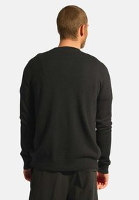 Svart tröja med rund halsringning och långa ärmar, tillverkad av ett mjukt material. Har en slät yta och en avslappnad passform.