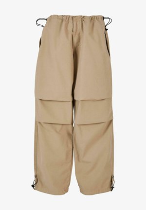 Beige cargo pants with an elastic waist, layered design, and side pockets. Features adjustable cuffs with toggles for a customizable fit.