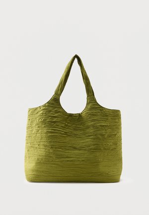 Sac fourre-tout vert avec un tissu texturé et froissé et de larges poignées, présenté sur un fond clair uni.
