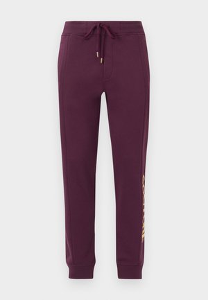 Bordeaux farvede sweatpants med snor i taljen, tapered ben og guld "COUTURE" print på venstre side. Blød, glat stofstruktur.