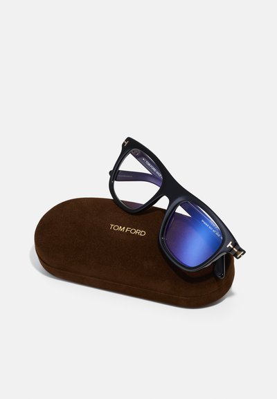 Óculos de sol com armação preta e lentes degradê em azul, colocados numa caixa de veludo castanho com a marca "TOM FORD" em relevo.