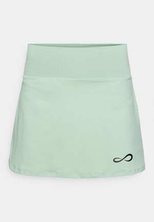Saia atlética verde clara com cintura elástica, textura suave e logotipo infinito preto no canto inferior direito.