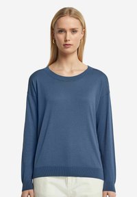 Blå stickad tröja med rund halsringning och långa ärmar, med en mjuk textur och ribbade detaljer vid ärmkanterna och nederkanten.