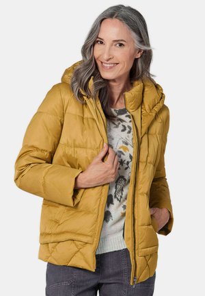 Geel pufferjack met een capuchon, gequilte ontwerp, ritssluiting, zijzakken en een relaxed fit, gedragen over een gebreid sweater.