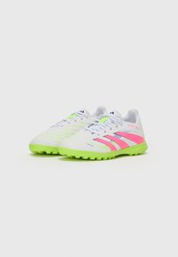 Chaussures de football blanches avec des semelles vert fluo, des accents roses et bleus, un dessus texturé avec des lignes horizontales, et un laçage à l'avant pour un maintien sécurisé.