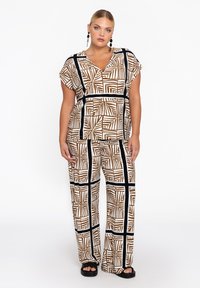 Passendes Outfit mit einem Kurzarmoberteil und weiten Hosen. Braunes und weißes geometrisches Blattformmuster, schwarze Akzente. Leichter Stoff.