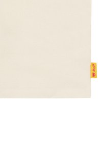 Tela color crema con una textura suave, con una etiqueta amarilla en la esquina inferior derecha que contiene un logo y un dobladillo cosido.