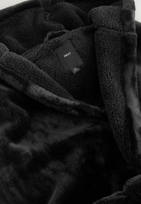 Black plush robe made from soft fleece material, featuring a large hood, front opening, and tag with "NEXT" branding.