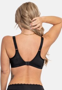 Black wireless bra with adjustable straps and a hook closure at the back. Smooth fabric and a wide underband for support.
