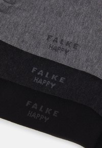 Tres pares de calcetines en diversas tonalidades de gris y negro, con un tejido de punto texturizado y la frase "FALKE HAPPY" impresa en los puños.